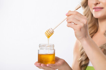 Fototapeta premium A Woman Carefully and Artfully Drizzling Golden Honey from a Jar Using a Dipper Tool
