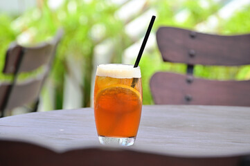 A glass of iced tea with lemon on the wooden table. Selective focus on the background.