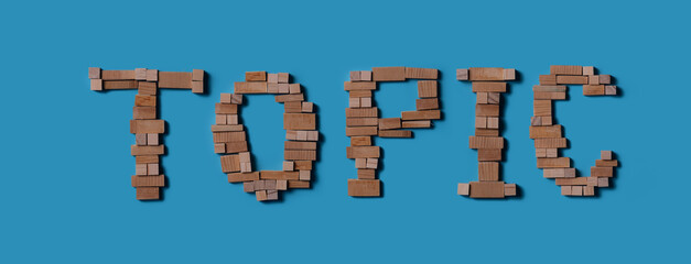 Naklejka premium “TOPIC” word made of wooden blocks on blue background, top view