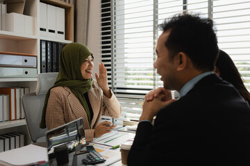 group of businessmen are discussing in an office. businessmen of different culture are meeting to make products that are appropriate and religiously correct. A businesswoman is wearing a hijab.