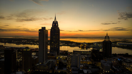 Obraz premium JULY 17, 2023, MOBILE, ALABAMA - USA - aerial view of Mobile Alabama skyline with Mobile Harbor and Port in background at sunrise