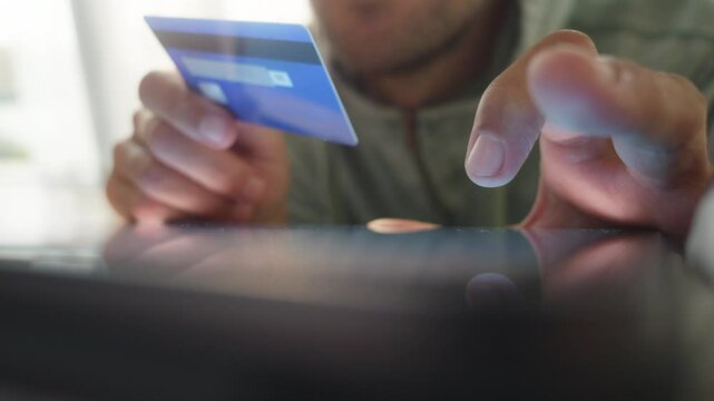 Man holding credit card and typing details on tablet for digital transaction close up. Secure e payment system and online shopping concept