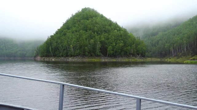 Zeya Reservoir. Picturesque views from a calm lake to green hills and forest. View from a boat. A boat sails along a calm lake.