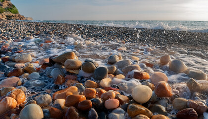 Obraz premium A collection of small rocks on the beach is wet with water splashes