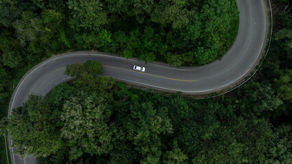 Aerial view electric vehicle car drive on forest road in green tree forest road, EV car electric vehicle car on forest road green energy and eco power, Ev car alternative sustainable renewable energy.