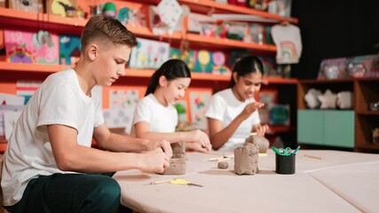 Group of happy smart diverse student working with clay art at pottery workshop. Multicultural attractive high school student modeling, smash, playing clay. Creativity activity concept. Edification
