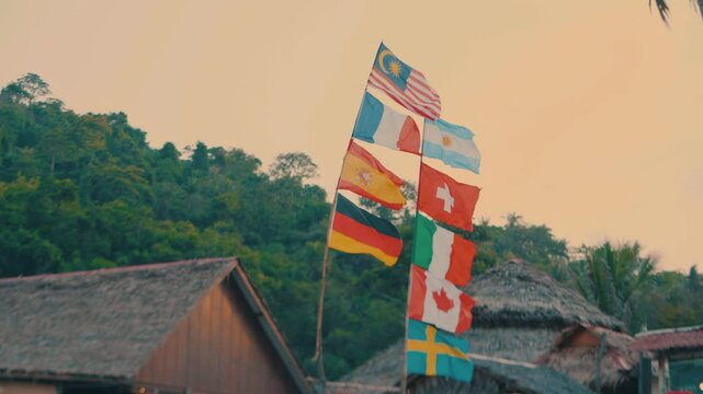 Multi nation flags waving on a single stick on a hut in Langkawi, Malaysia during sunset.