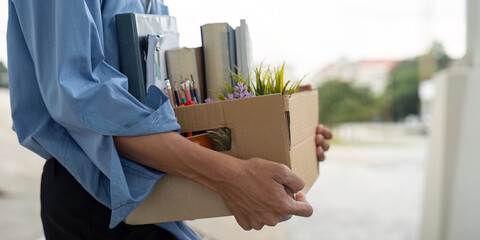 Close-up of Asian man holding personal items after resigning