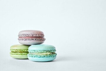 Stack of three colorful French Macarons, cakes with different flavors stacked in a pyramid, mint, apple, currant flavor. homemade dessert, macaroons aquamarine, green, purple color on gray background