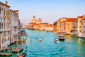 June 25, 2019. Venice, Italy. Beautiful view of traditional Gondola on famous Canal Grande with Basilica di Santa Maria della Salute in golden evening light at sunset in Venice, Italy.
