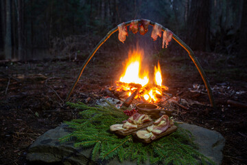 Cooking meat in the wild on a campfire. Bacon pieces are fried on a campfire