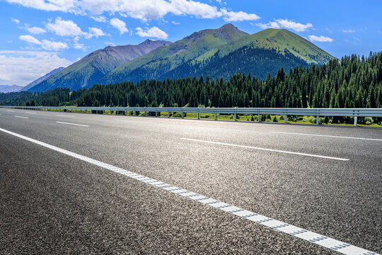 Countryside asphalt road and green forest with mountain nature landscape on a sunny day. Road trip.