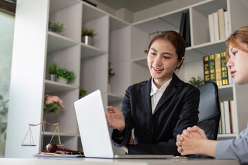 Friendly Asian lawyer presenting information on laptop