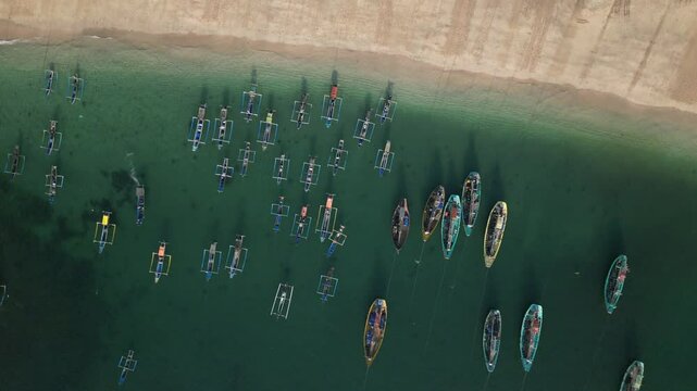Drone footage over Papuma beach with clean green water and fishing boats sailing from shoreline
