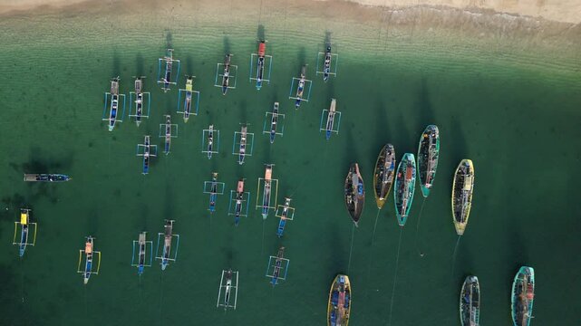 Drone footage over Papuma beach with clean green water and fishing boats sailing from shoreline