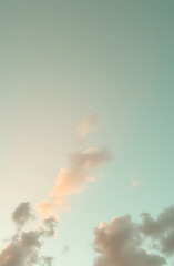 Obraz premium Pastel peach and mint green sky with floating clouds and a hint of starlight, peaceful phone wallpaper.