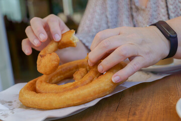 woman's hands eating churros in a bar, a typical spanish sweet.