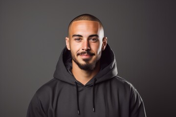 Obraz premium A man with a shaved head and a beard is wearing a black hoodie and smiling