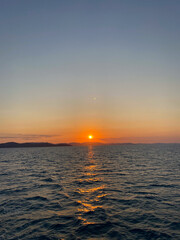 orange sun setting over calm blue ocean, Whitsundays, Australia