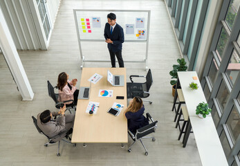 Group of business people are gathered in a meeting room, discussing and sharing ideas around a large conference table.