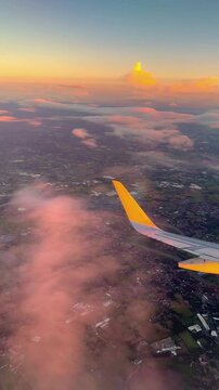 Sunset flight. Sunset through airplane window. Flight footage with aircraft wing and city view from an airplane window. Sunset view. View from aircraft porthole. Airplane travel aviation background. 