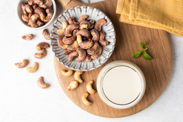 Cashews and glass of cashew milk on a wooden board. Top view with copy space