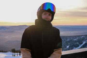 portrait of a man in a ski suit against the backdrop of a mountain sunset