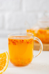 Hot sea buckthorn tea with orange, ginger, honey and cinnamon in glass cups. Herbal vitamin c tea. Vertical orientation.