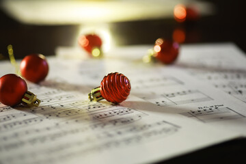 Festive Red Christmas Ornaments on Sheet Music with Holiday Cheer and Warm Lighting