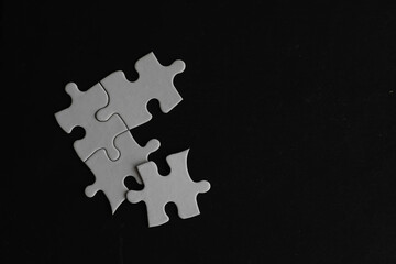 White Puzzle Pieces on Black Background Symbolizing Problem Solving and Teamwork