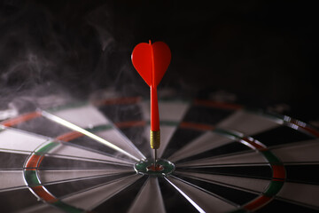 Red Dart Hitting Bullseye on Dartboard with Smoky Background - Precision and Accuracy Concept