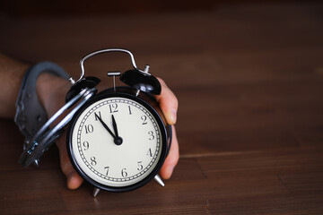 Hand Holding Alarm Clock with Handcuffs Symbolizing Time Constraints and Restrictions