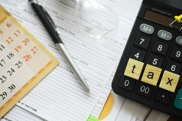 Calculator With 'Tax' Scrabble Tiles on Documents Amidst Pen and Calendar, Conceptualizing Financial Planning