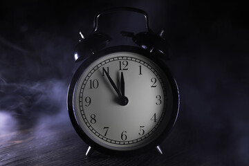 Vintage Alarm Clock on Wooden Table with Smoky Background in Dark Ambience