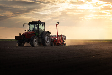 Obraz premium Farmer with tractor seeding in sunset