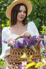 Girl with a hat and a basket in lupine flowers