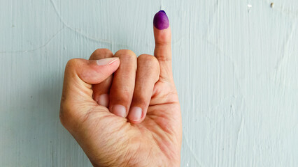 Hand with purple ink on the little finger, as a sign of having voted in the general election in...