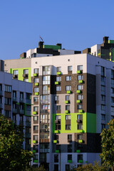 Cityscape on a summer day, modern buildings and houses against the blue sky 