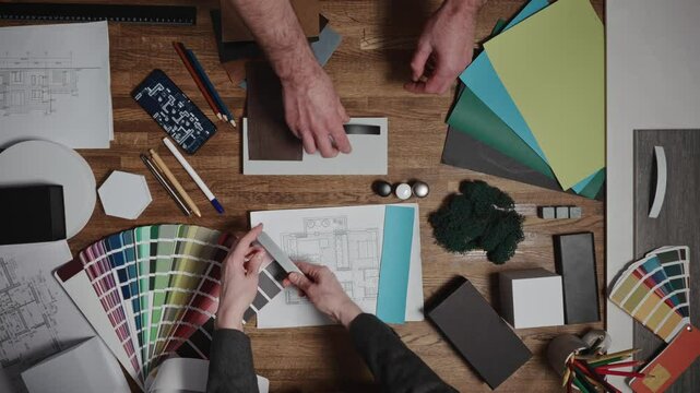 Design and architecture studio. Close-up, male and female hands of interior designers working with samples of materials and color palettes. Working on an apartment project