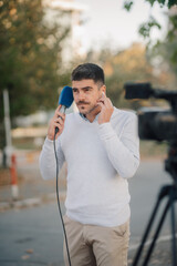 Reporter receiving instructions while recording a live report outdoors