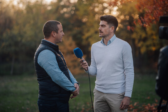 Journalist interviewing farmer in a field at sunset