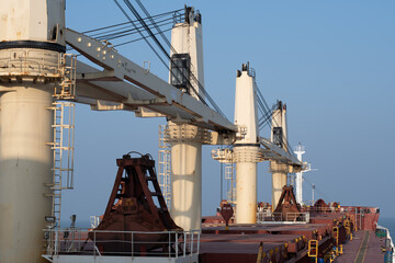 Obraz premium cargo handling cranes, grabs in parked position on board of a bulk carrier ship