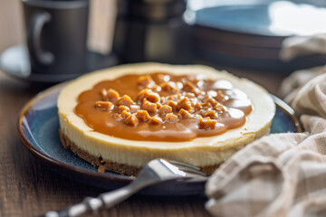 Cheesecake with caramel topping on plate on wooden table.