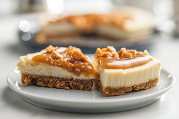 A cut piece of  cheesecake with caramel topping on plate on kitchen table.