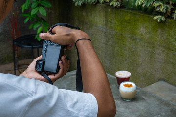 male asian photographer using digital mirrorless camera for capturing food photography, in a cafe environment 