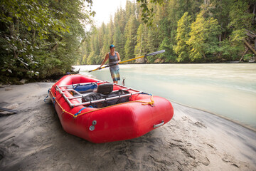 Man holds oar while prepping river raft for an adventure