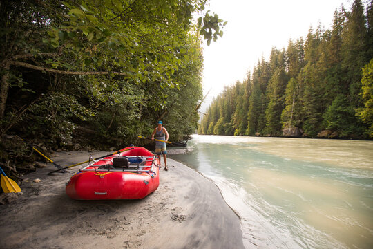 Man preparing raft, oars and gear before rafting down a river.
