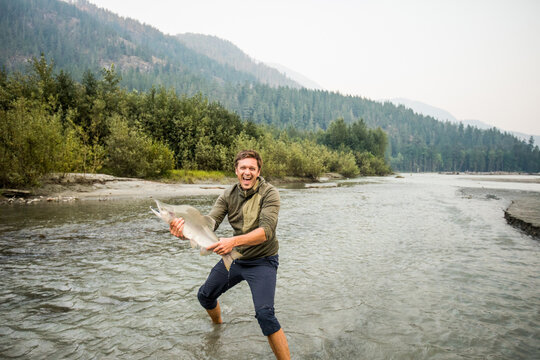 Excited fisherman holds a Pink Salmon in the Squamish River, B.C.
