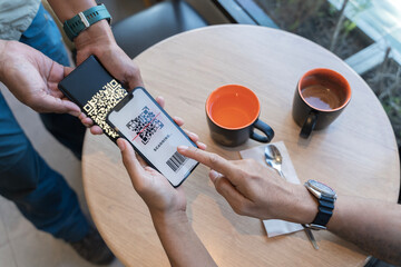 Focus on Scan here to pay text. Close up of hands Scaning QR code for digital contact less payment after shopping.
