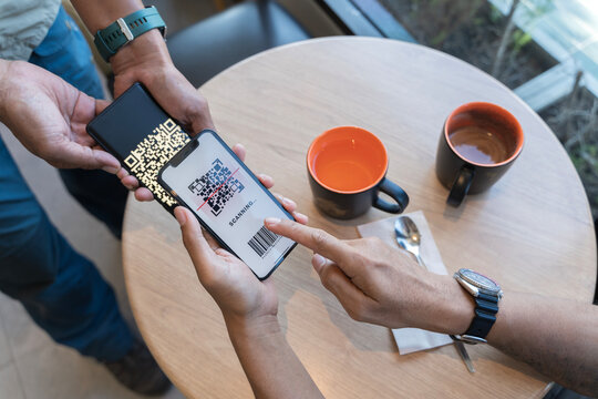 Focus on Scan here to pay text. Close up of hands Scaning QR code for digital contact less payment after shopping.